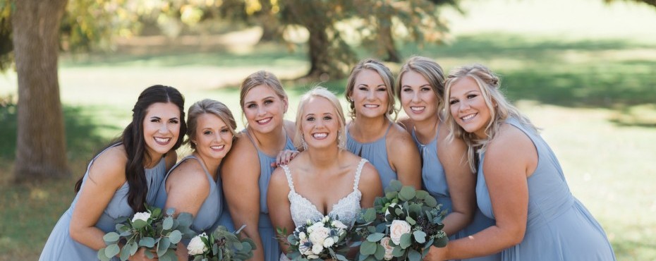 Bridal party posing for an outdoor picture holding bouquets of greenery